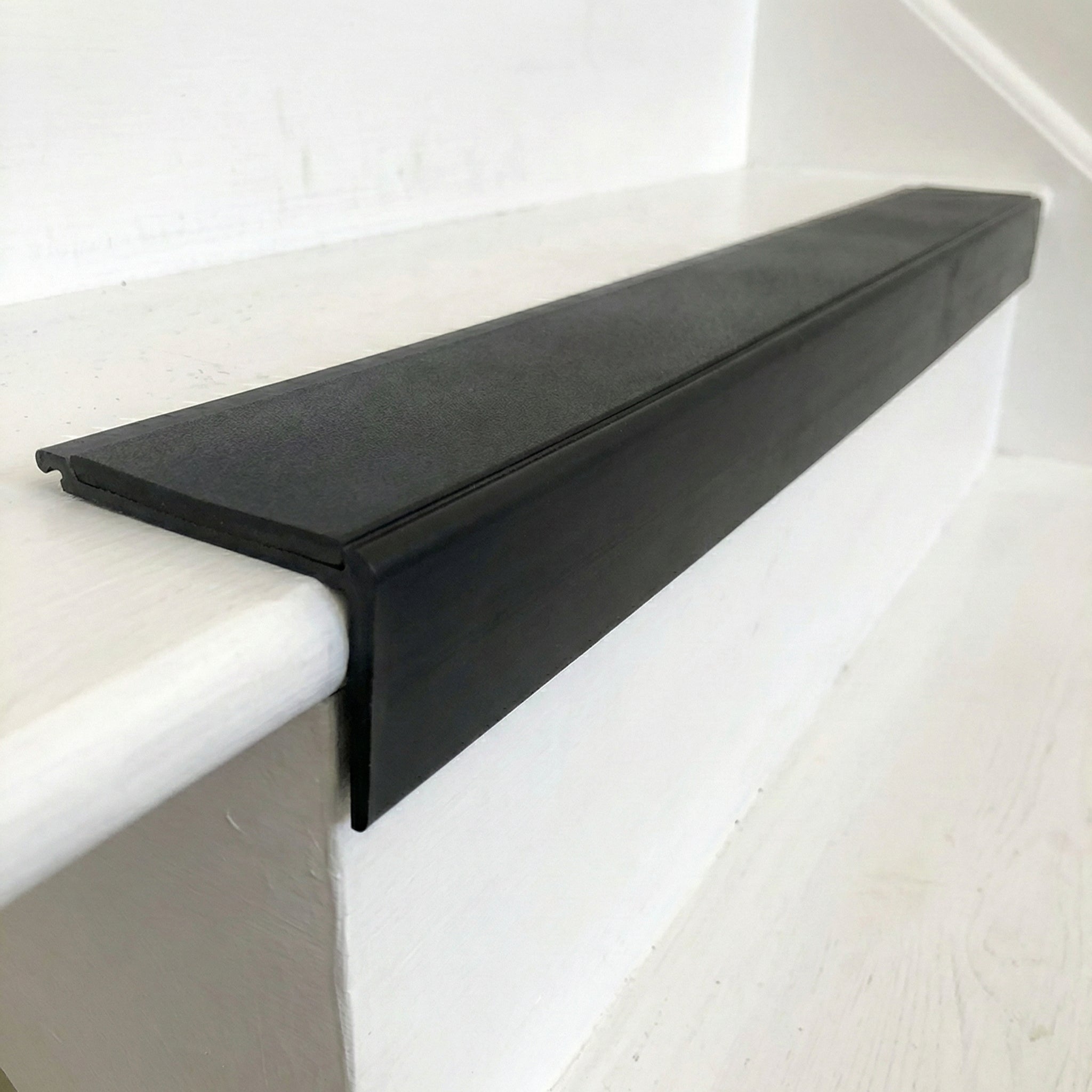 Heavy-duty PVC stair nosing protecting carpeted stairs in UK commercial facility